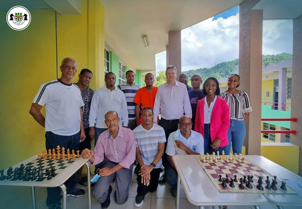 Photo of GM Nigel Short during his visit to Dominica in October 2021. Standing (left to right): Morris Burton, Larry Thomas, Carlton Morvan, Mitchel Davis, Nigel Francis, GM Nigel Short, Lyndon Auguiste, Robert Bridet, Tris-Ann Richards (President of the St. Lucia Chess Federation), Shawnalee Gordon. Kneeling (left to right): Ross Boyd, Daniel Scotland, Edgar Berridge. This photo was captured during a simultaneous exhibition with GM Nigel Short.